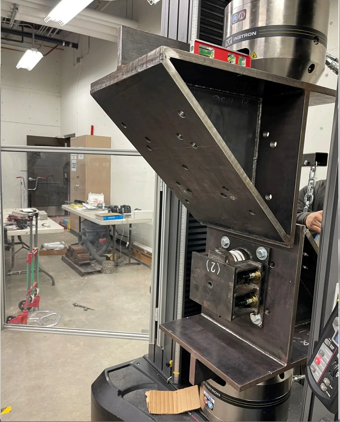 Custom shear test fixture mounted on an Instron universal testing machine evaluating an SSI isolator in pure shear